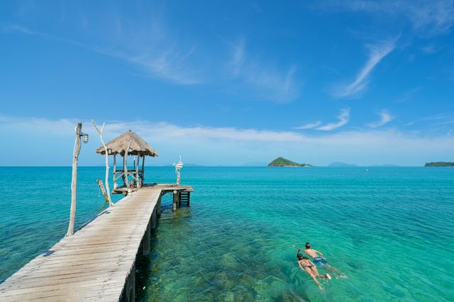 Young couple of tourists snorkel in crystal turquoise water near